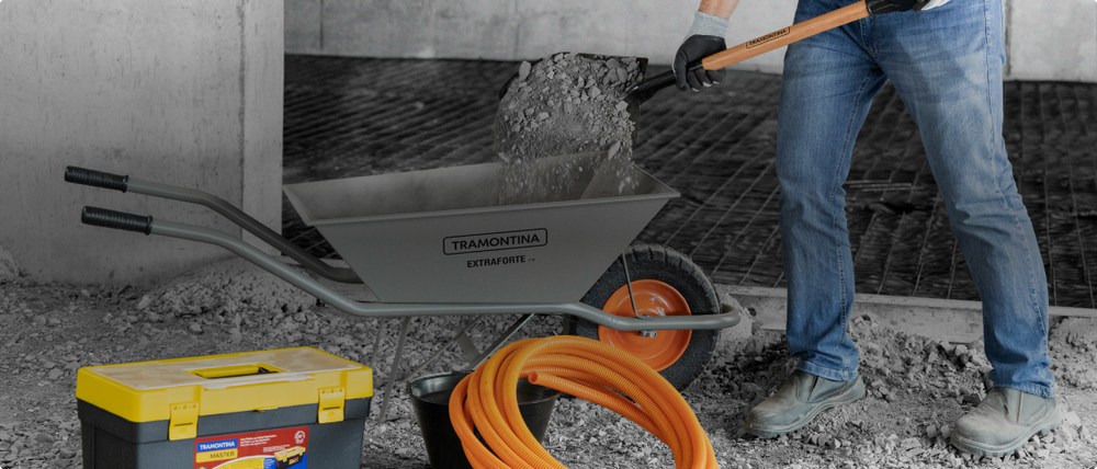 Person placing gray in a Tramontina wheelbarrow.