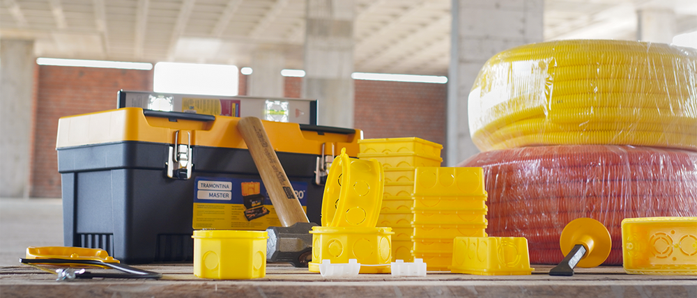 Caixa de ferramentas com itens amarelos, martelo e materiais de construção em um ambiente industrial.